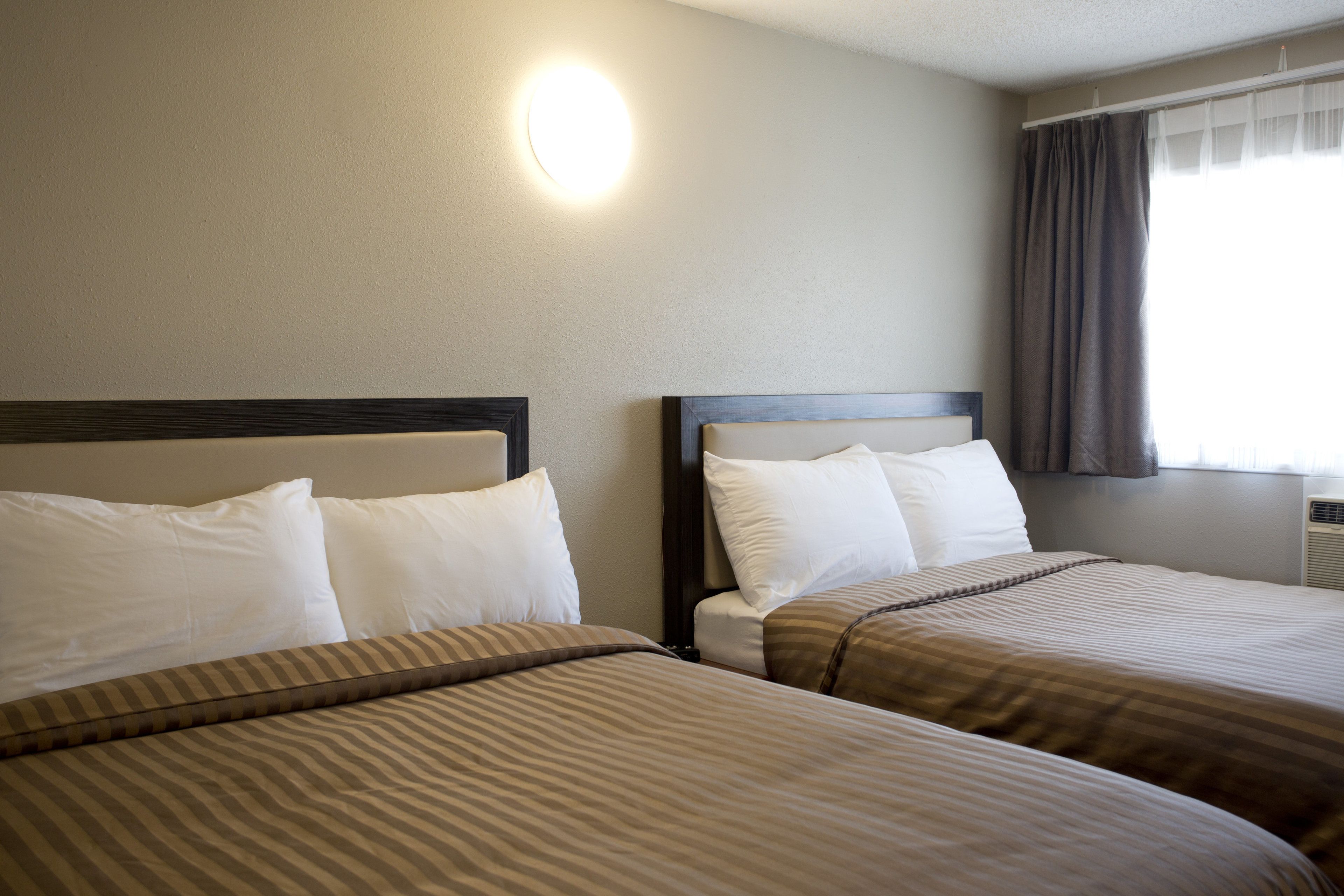 Ein Hotelzimmer mit zwei Betten, jeweils mit weißen Kissen und gestreifter Bettwäsche.