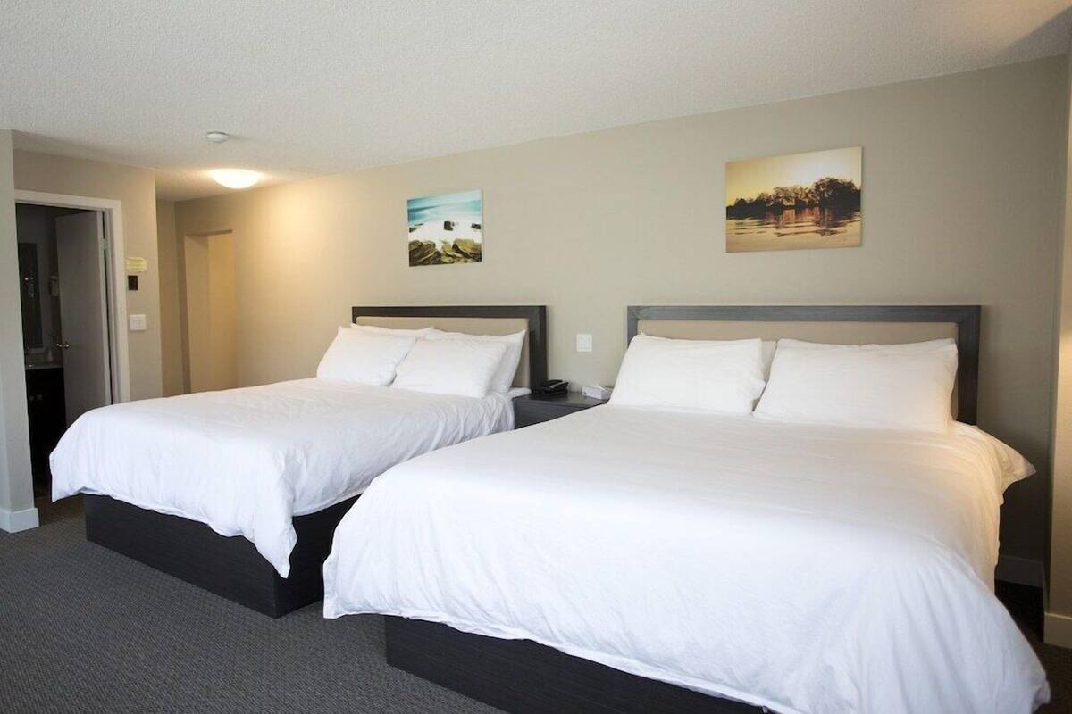 A hotel room with two beds, a door, and two wall-mounted pictures.