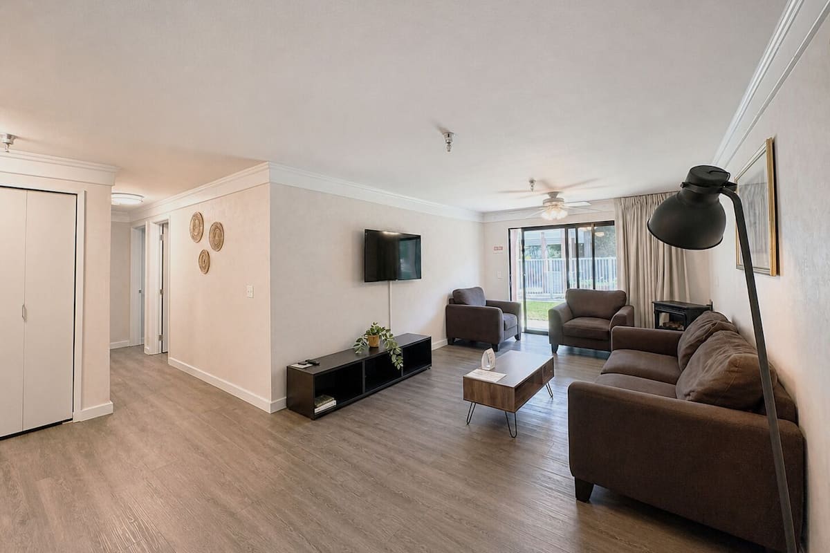 Una sala de estar moderna con un televisor de pantalla plana, dos sofás, una mesa de centro y una estantería.