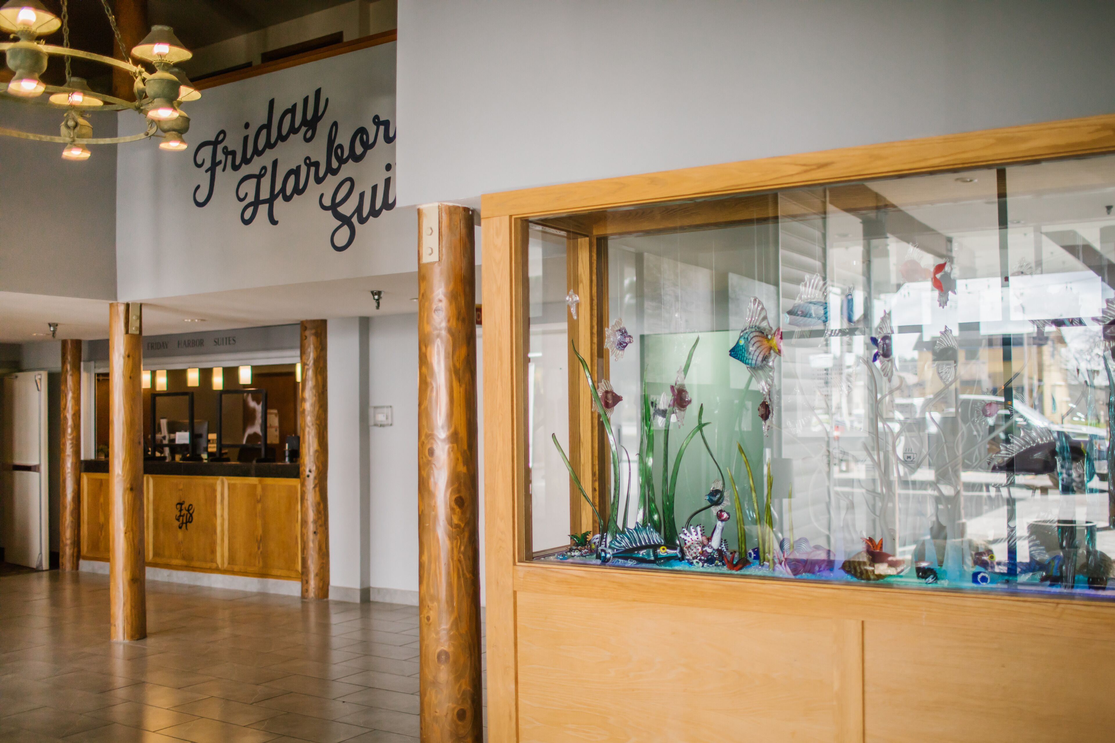 Un área de recepción con un mostrador de madera, una vitrina de vidrio con objetos decorativos y un letrero que dice "Friday Harbor Suites".