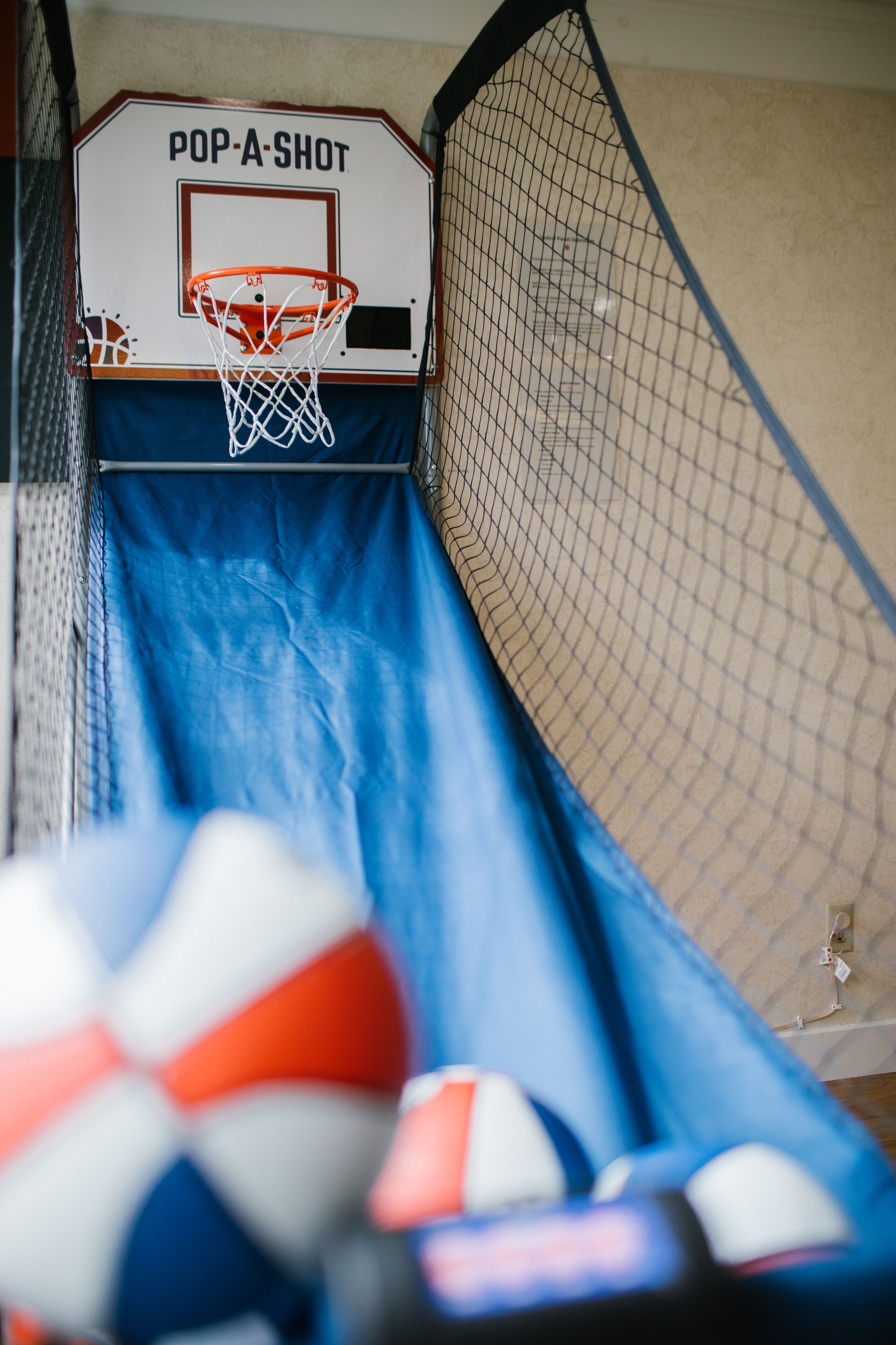 A basketball hoop with a net, a blue slide, and a volleyball in the foreground.