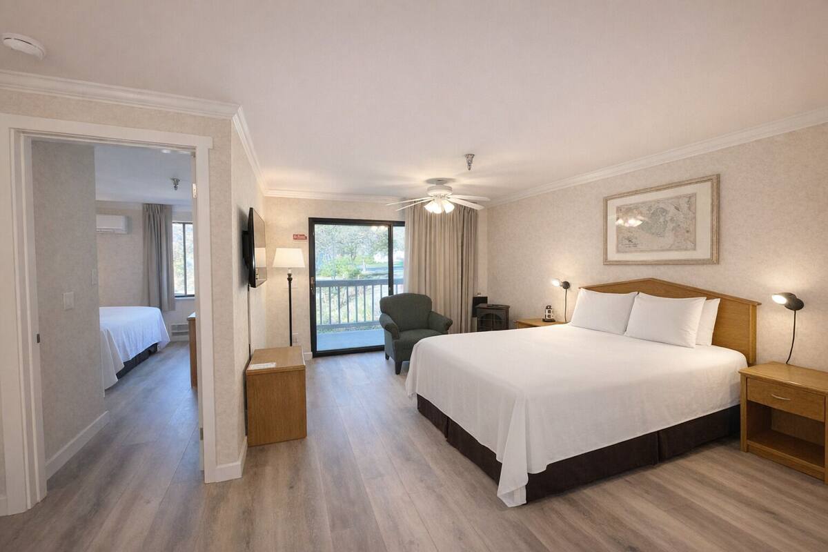 Habitación de hotel con una cama grande, un escritorio, una silla, un balcón y un ventilador de techo.
