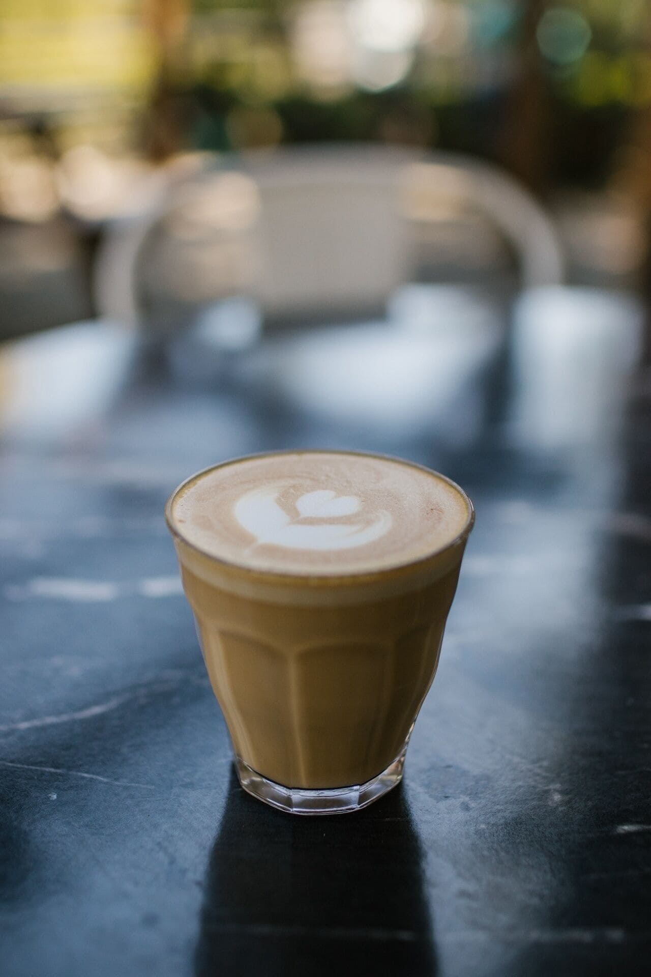 A glass of coffee with latte art on a table.