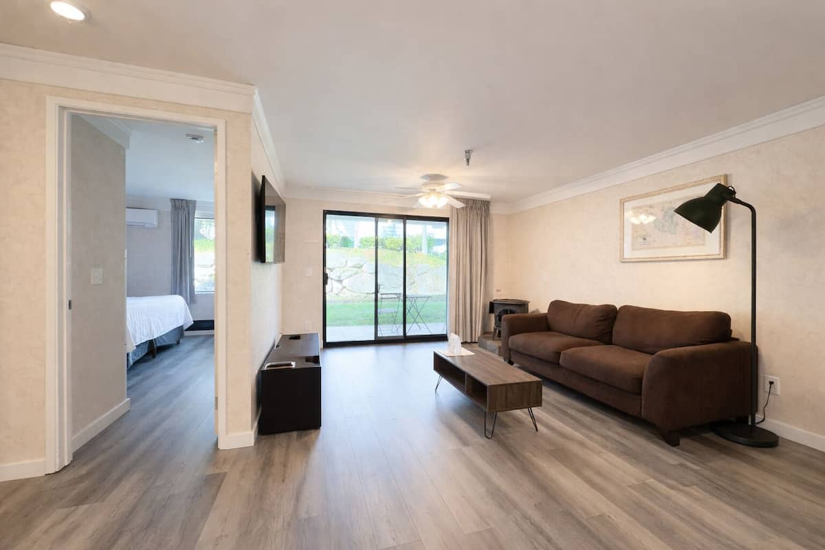 Una sala de estar moderna con un sofá marrón, una mesa de centro y un televisor montado en la pared.