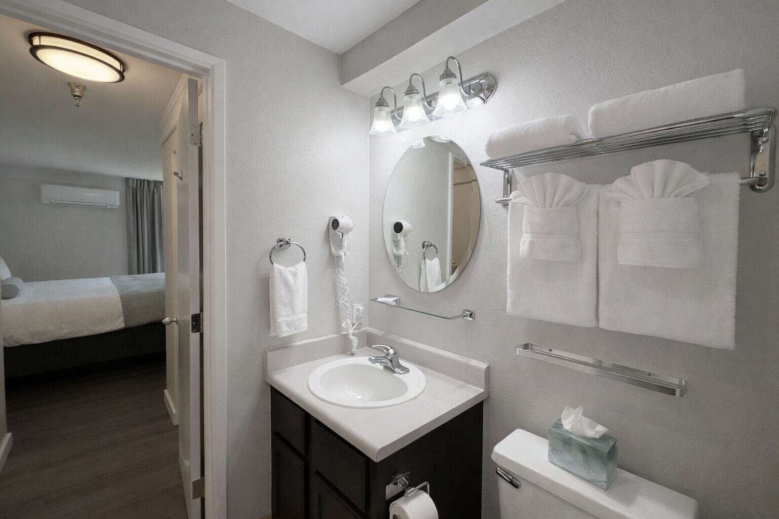 Une salle de bain d’hôtel équipée d’un lavabo, d’un miroir, d’un porte-serviettes et de toilettes.
