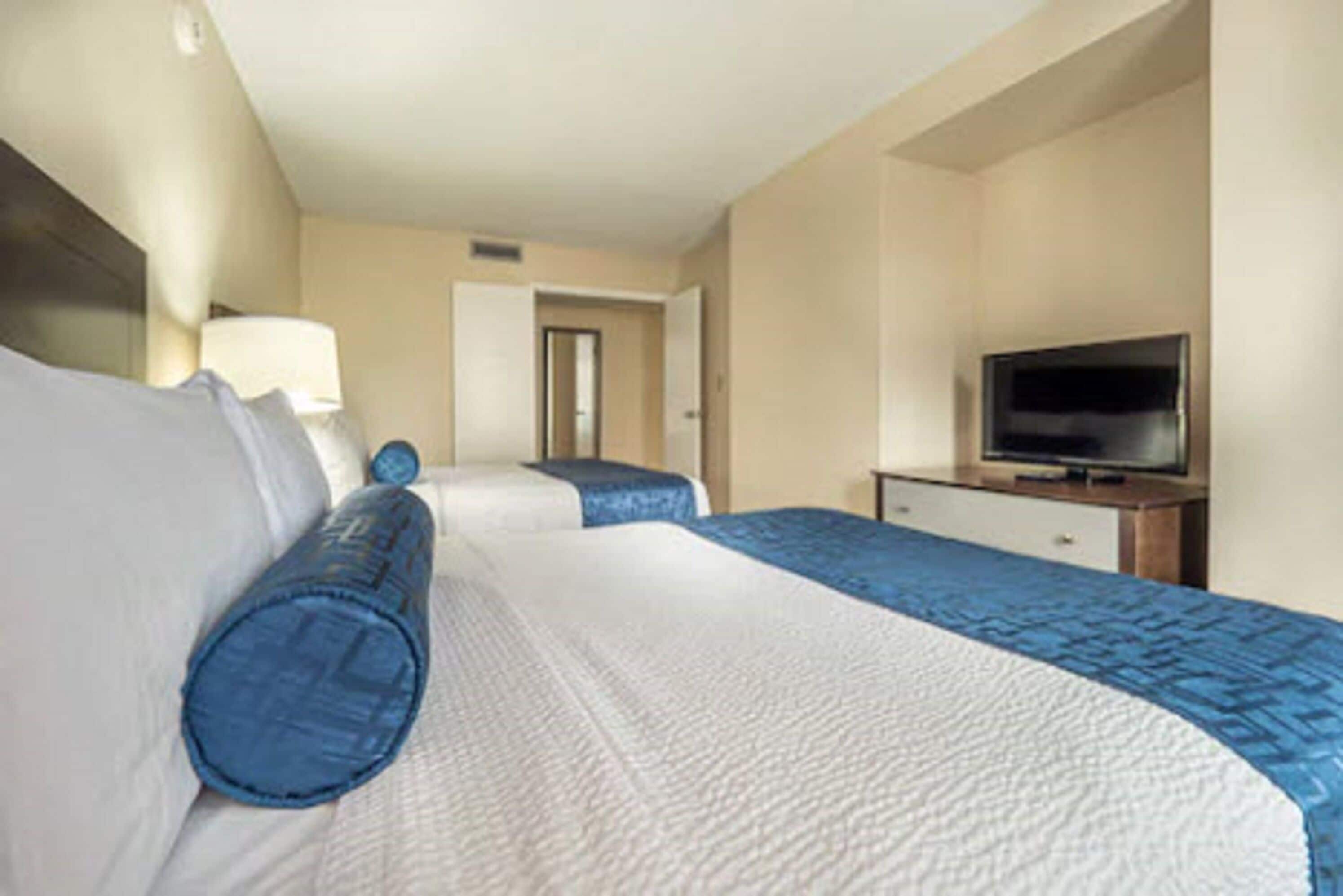 Habitació d'hotel amb dos llits, una televisió i una porta que dona a una altra habitació.