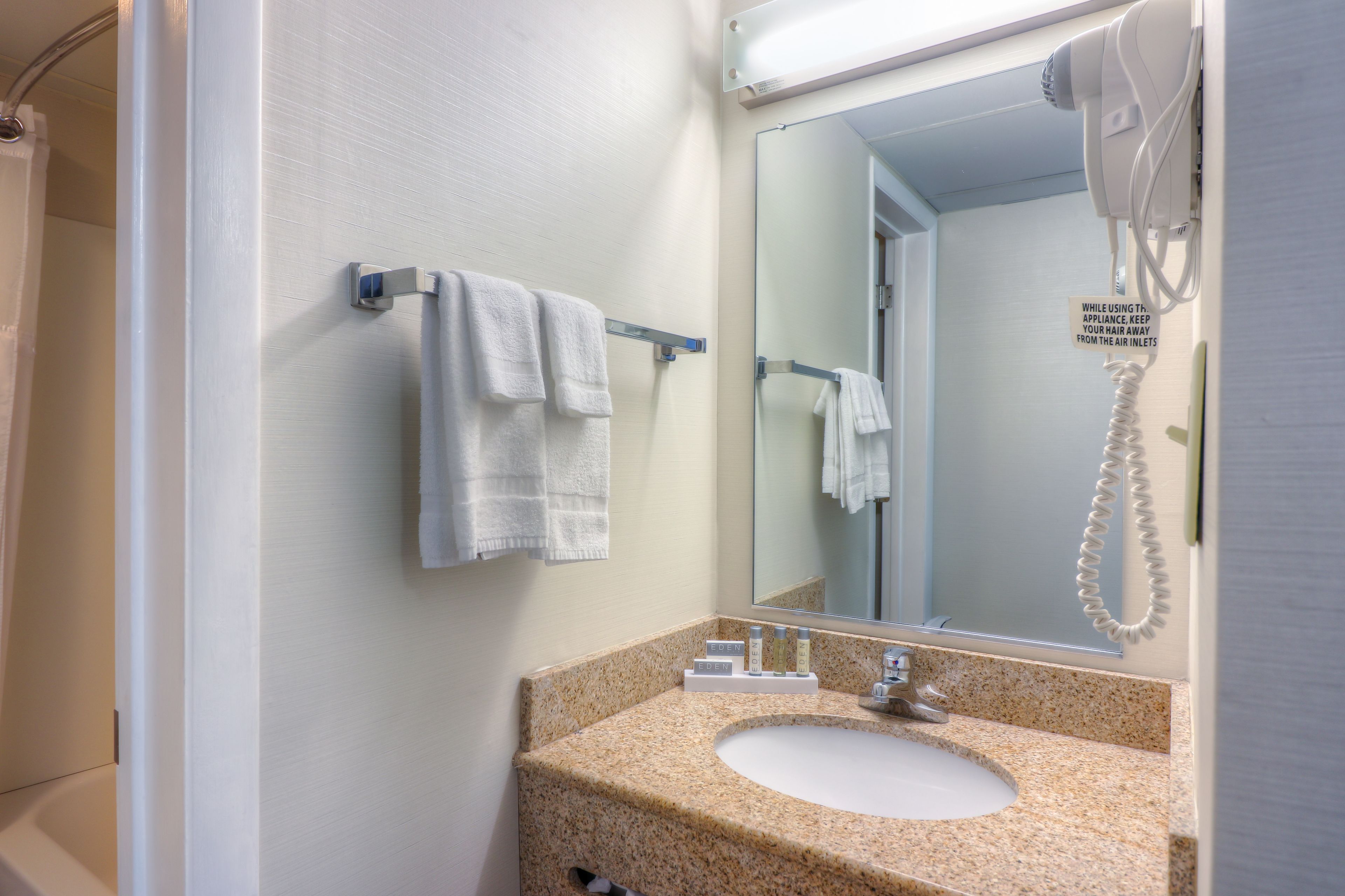 Un baño con lavamanos, espejo, perchero y secador de pelo.
