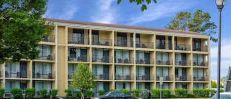 A multi-story hotel with a uniform facade, balconies, and a parking lot.