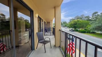Enjoy a balcony with a street view, featuring a chair and glass railing.