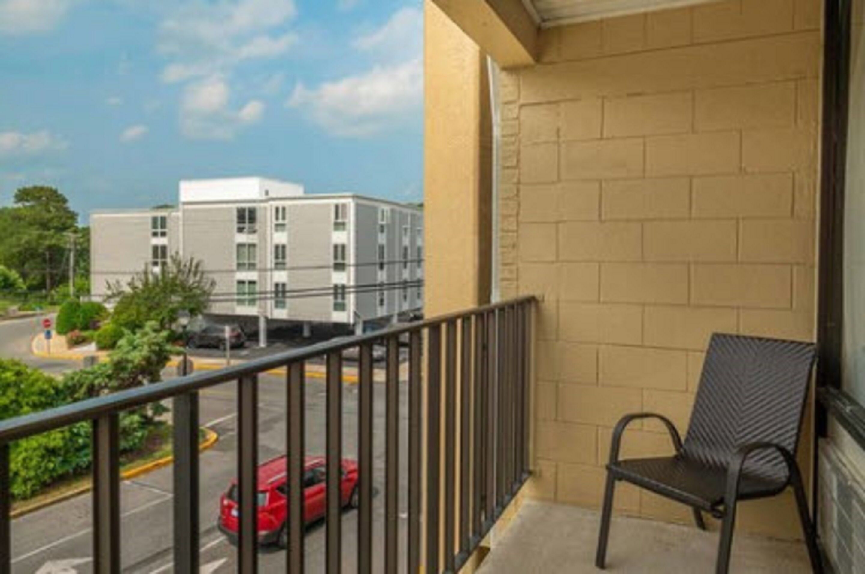 A balcony with a metal railing and a single black chair.