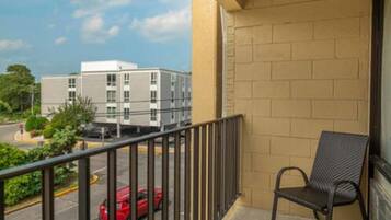A balcony with a metal railing and a single black chair.