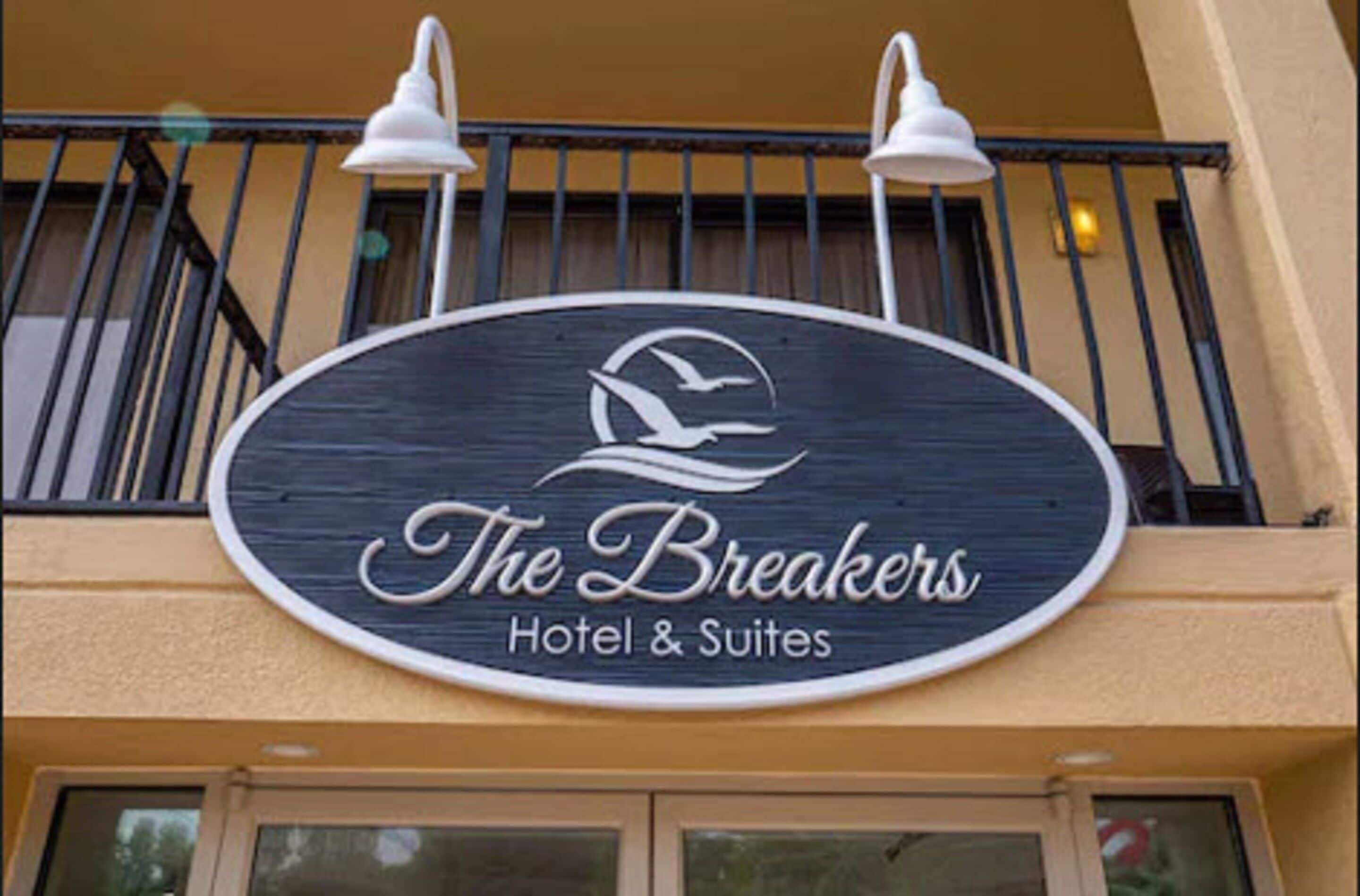 A hotel sign with the name "The Breakers Hotel & Suites" and a logo featuring a bird and waves.