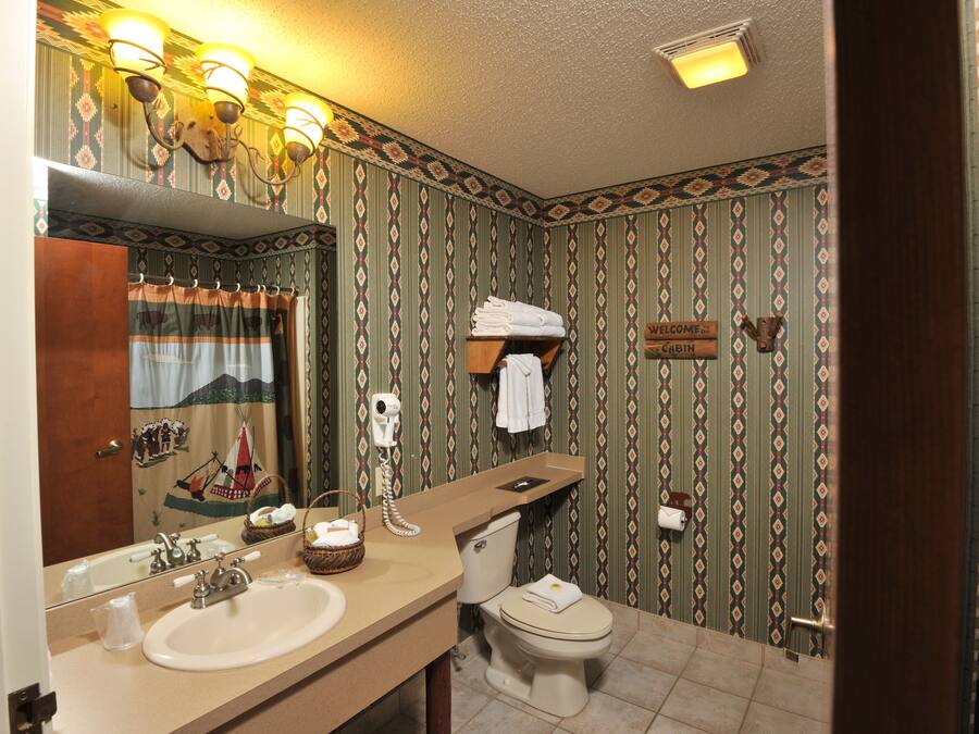 Ein Badezimmer mit Waschbecken, Spiegel, Handtuchhalter und Toilette.