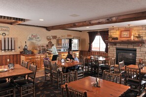 A cozy restaurant with wooden furniture, a stone fireplace, and a counter with a beverage dispenser. - Cedar Creek Hotel Wausau - Rothschild (Rothschild)