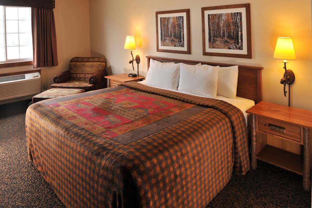 Ein Hotelzimmer mit einem großen Bett, zwei Nachttischen, einem Sessel und zwei Wandlampen.