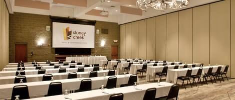 A conference room with rows of tables and chairs, a projector screen, and a chandelier.