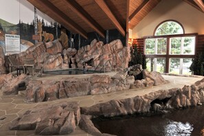 A rock garden with a pool, wooden deck, and a chair. - Cedar Creek Hotel Wausau - Rothschild (Rothschild)