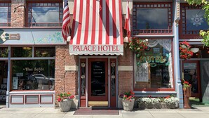 The exterior of the Palace Hotel with a red and white striped awning, brick facade, and flower planters at the entrance. - Palace Hotel Port Townsend (Port Townsend)