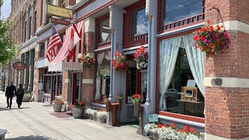 A hotel with a red and white striped awning, a sign indicating no vacancy, and a plaque on the building.