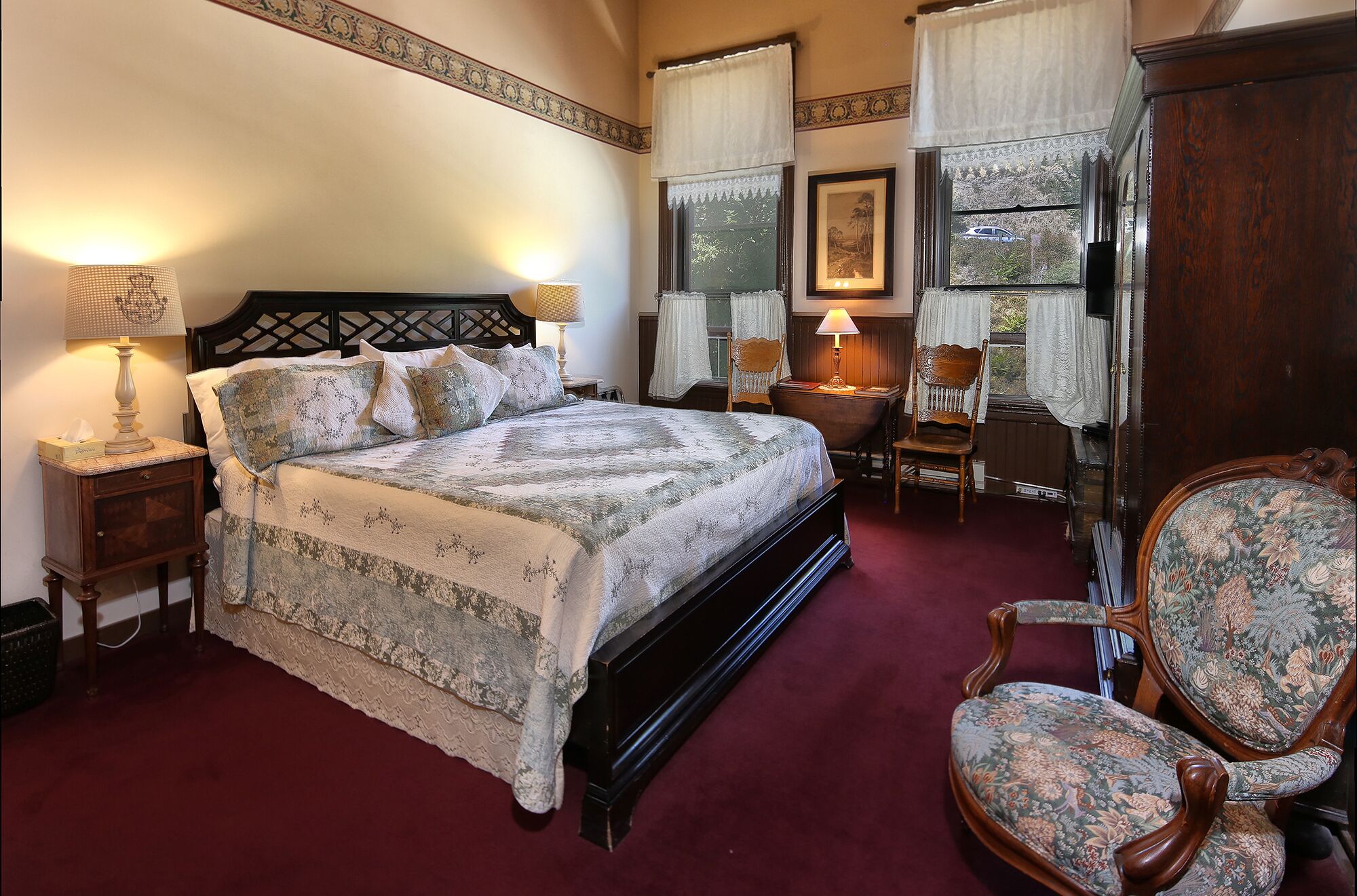 A traditional bedroom with a large bed, two bedside tables, a wooden chair, and a wooden wardrobe.