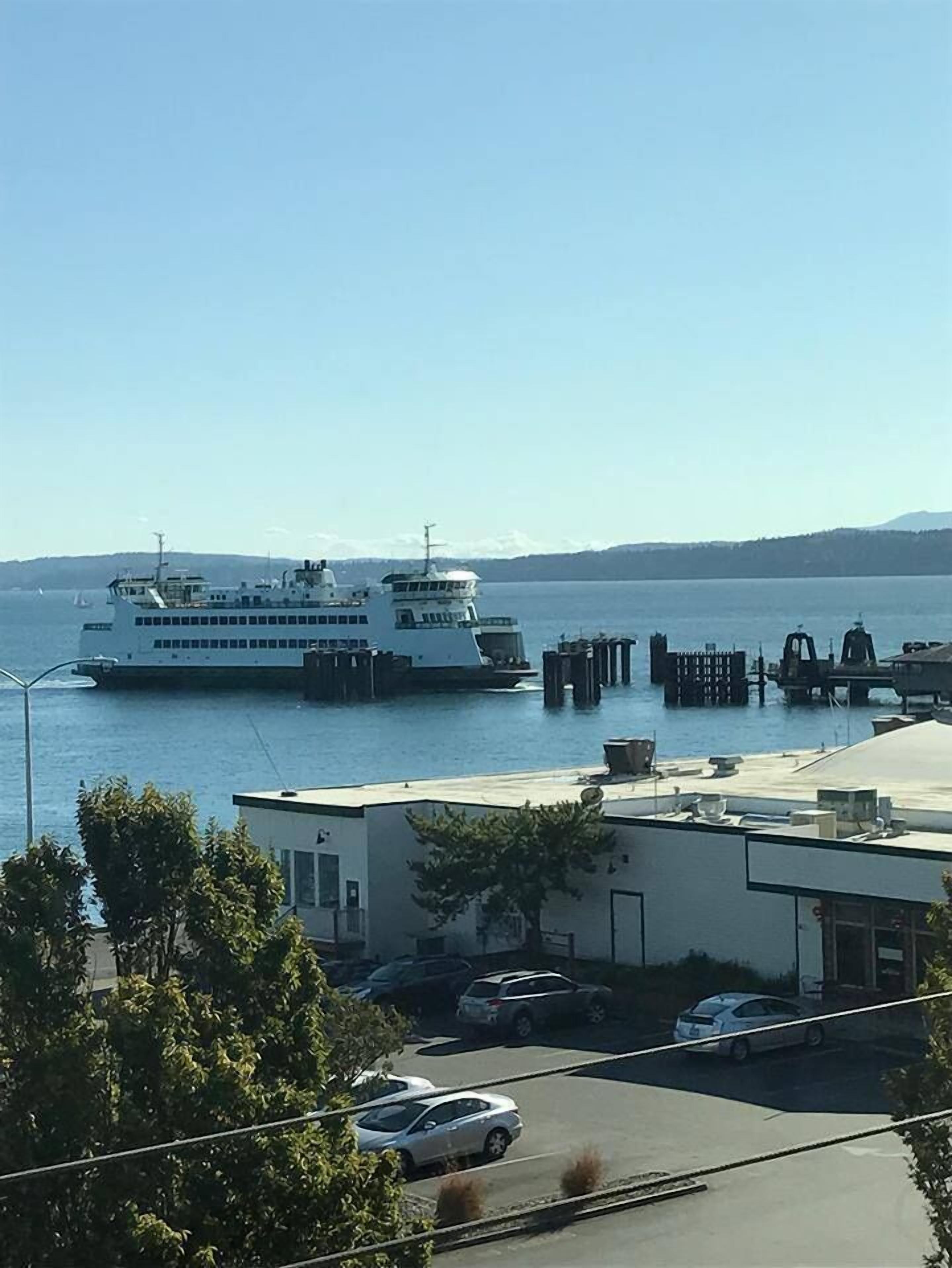 Un ferry amarrado en un muelle con vistas despejadas al agua y montañas distantes.