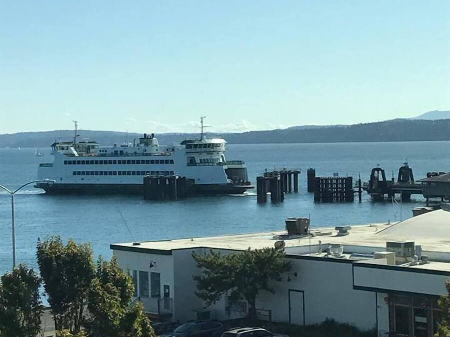 Un ferry amarrado en un muelle con vistas despejadas al agua y montañas distantes.