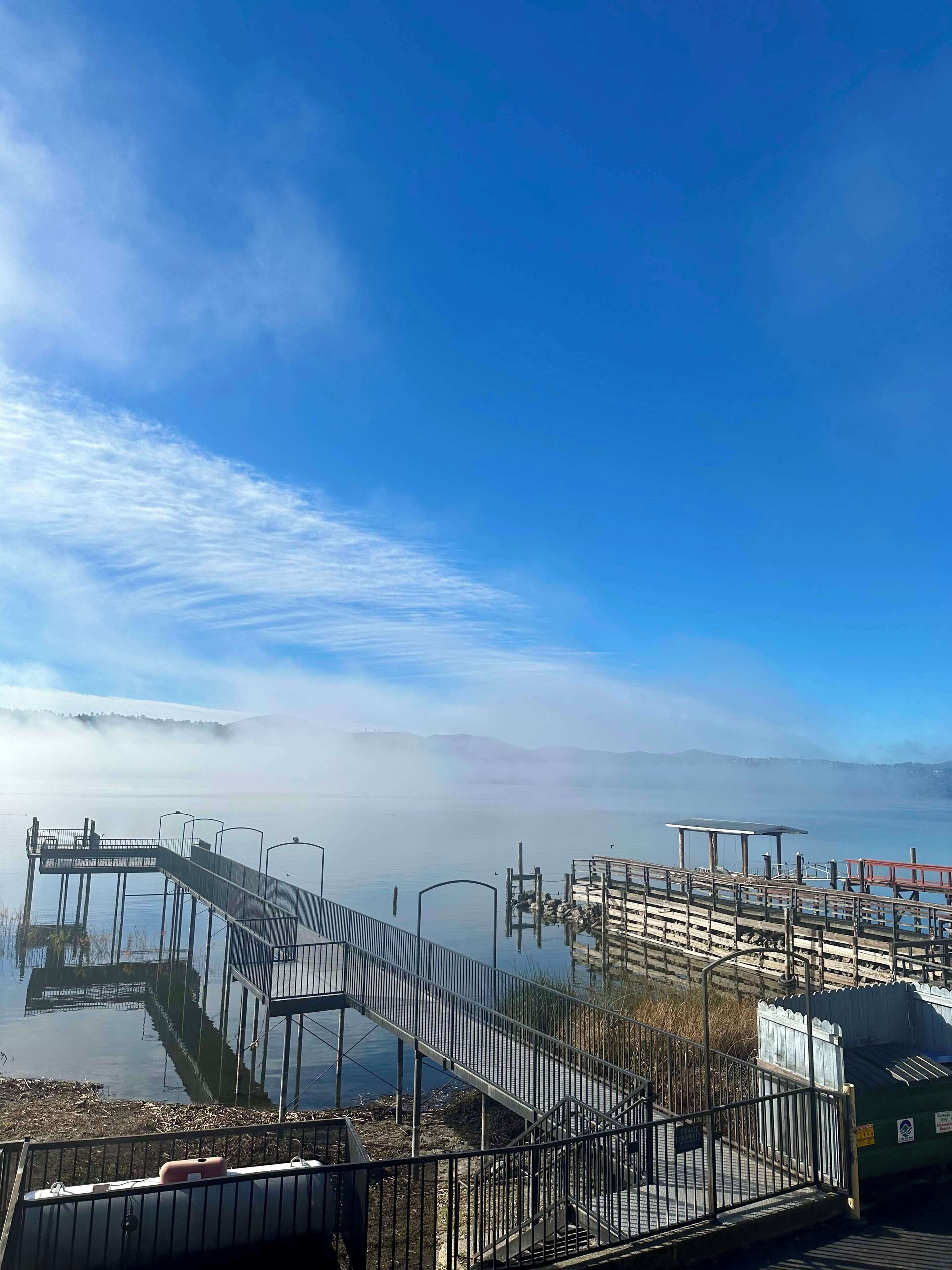 A pier extending into calm water with a clear sky above.