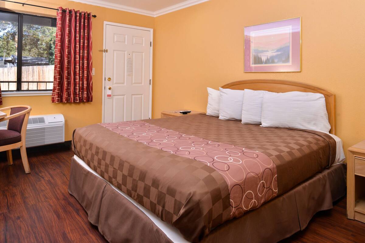 Een hotelkamer met een groot bed, een stoel, een bureau en een raam met gordijnen.