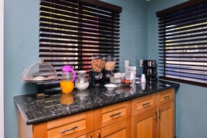 Una cocina con encimera de granito, armarios de madera y cafetera.