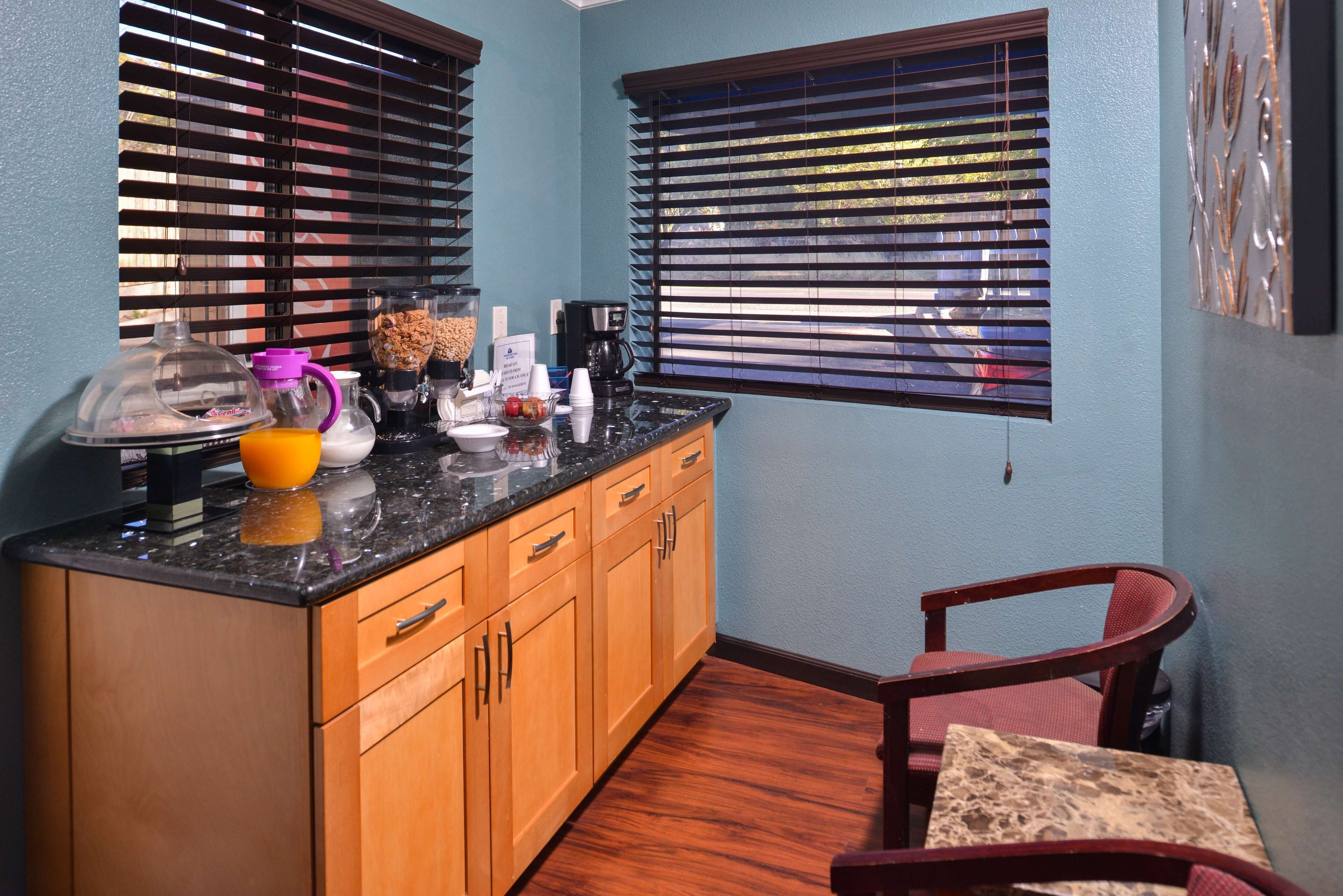 A compact kitchen with wooden cabinets, a granite countertop, and a coffee maker.