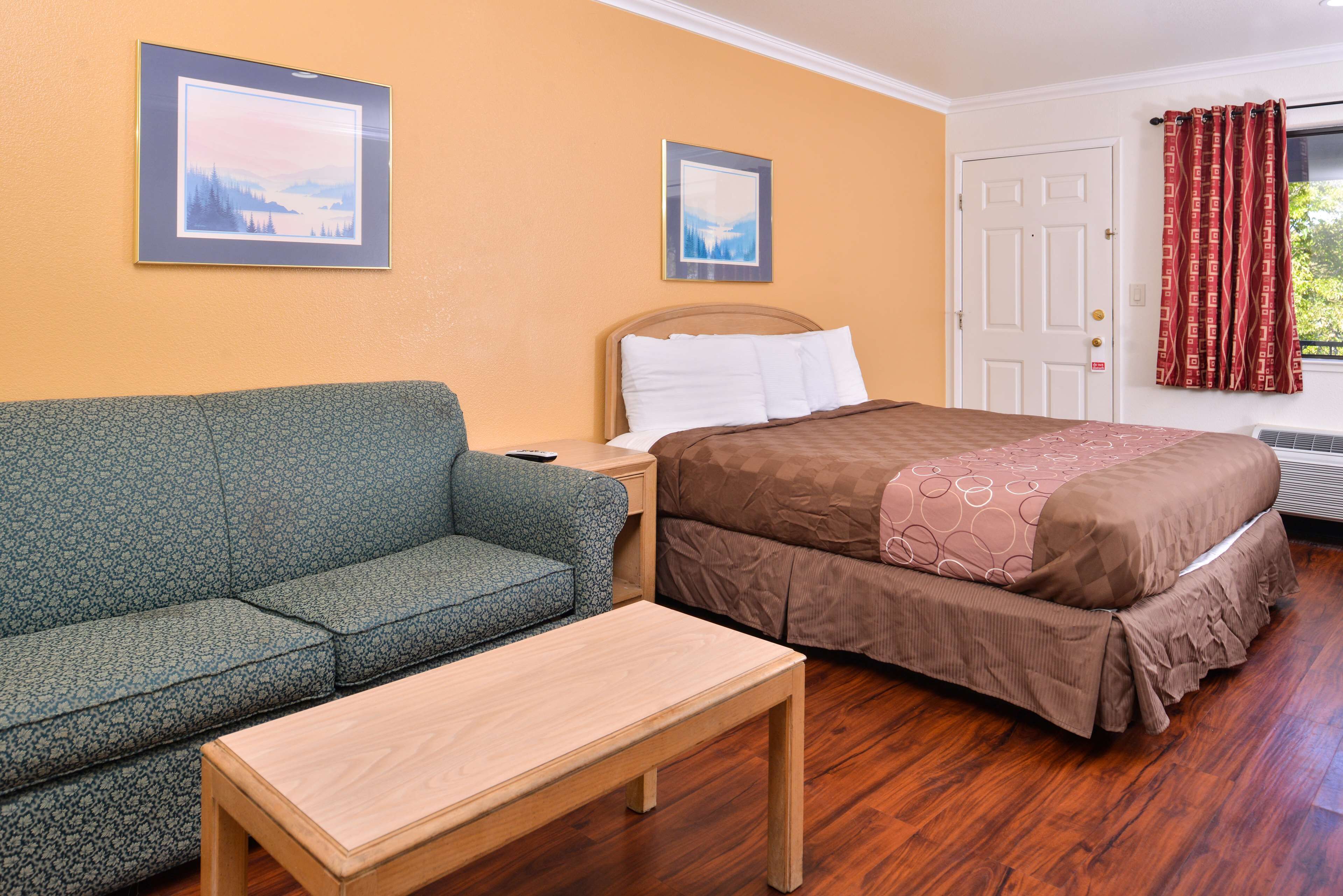 Een kamer met een bed, een slaapbank en een tafel.