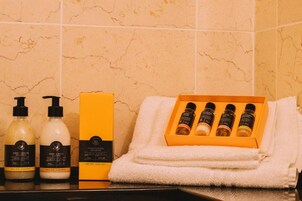 Kylpyhuone, jossa on hygieniatuotteita, kuten shampoopullo, vartalovoidepullo ja suihkugeelipakkaus.