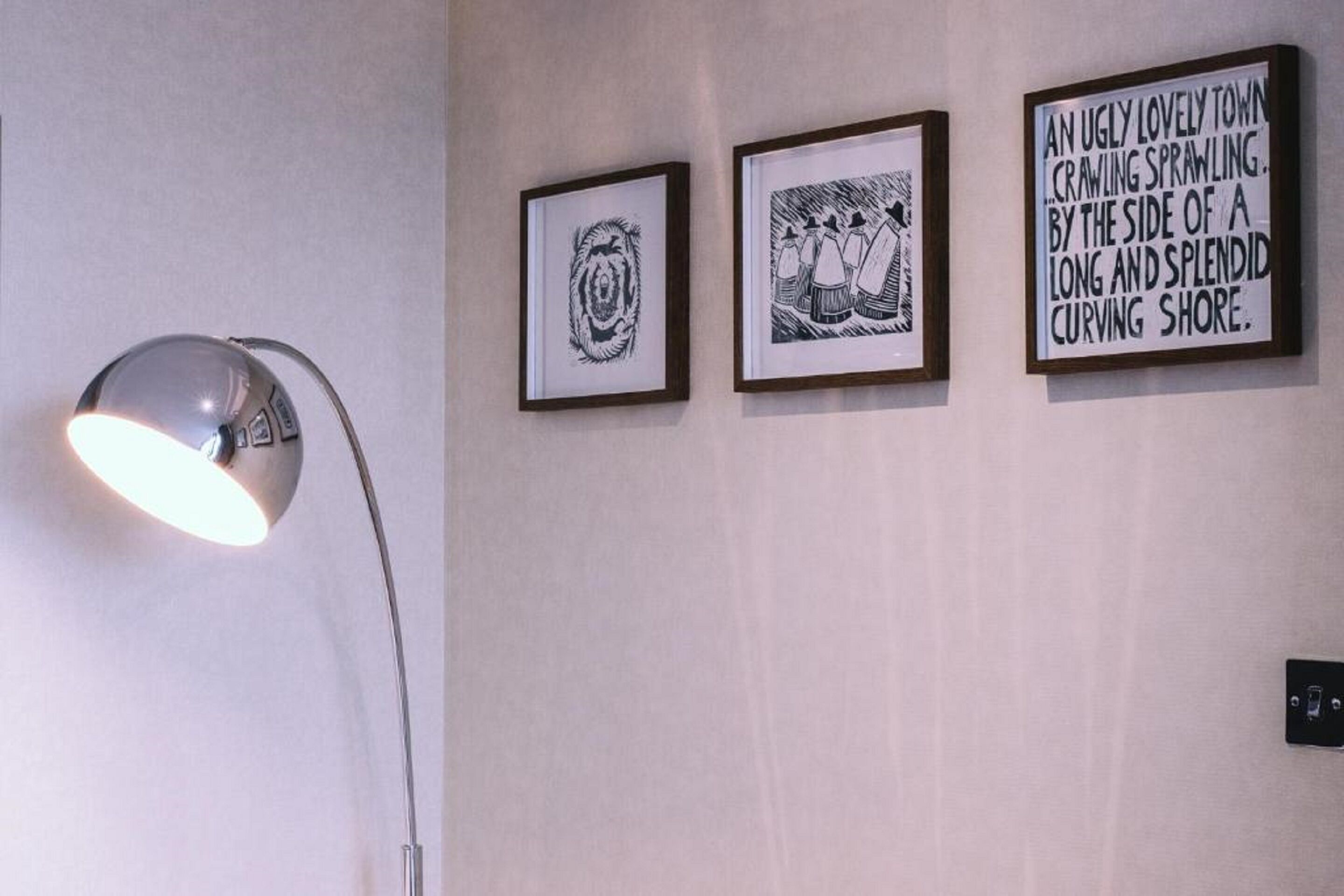 Una pared con tres cuadros enmarcados y una lámpara de pie.