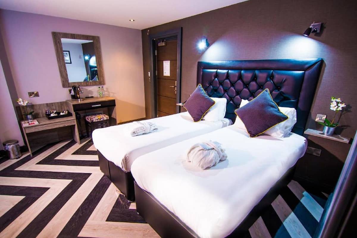 Une chambre d’hôtel avec deux lits, une coiffeuse avec un miroir et un design moderne.