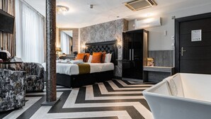 Une chambre d’hôtel moderne dotée d’un grand lit, d’un coin salon avec un fauteuil, d’une baignoire et d’une armoire.
