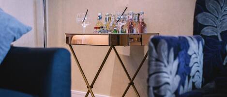Una habitación con una pequeña mesa que sostiene varias botellas y vasos, presumiblemente para bebidas.