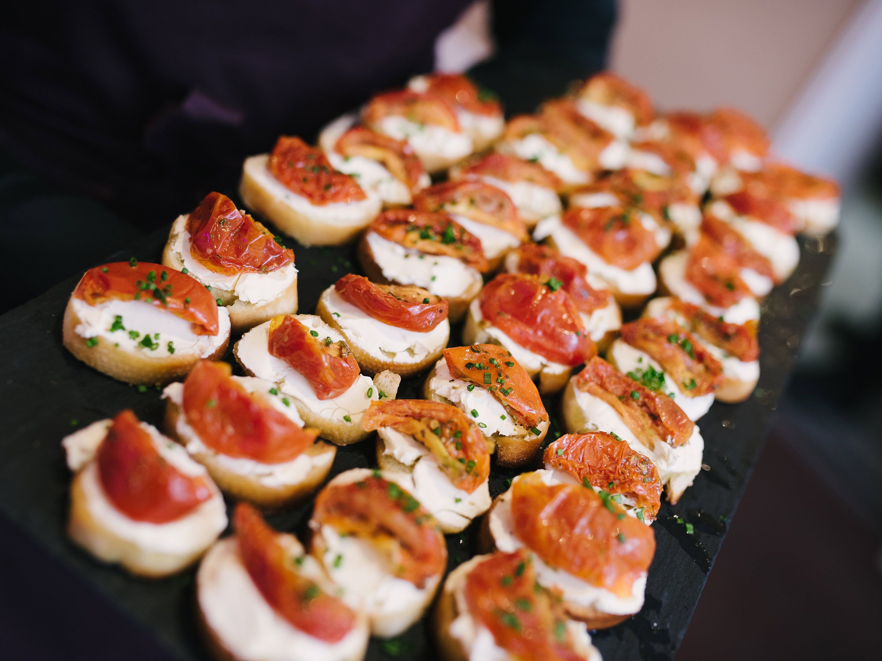 A tray of appetizers with bread, cheese, and tomato slices.