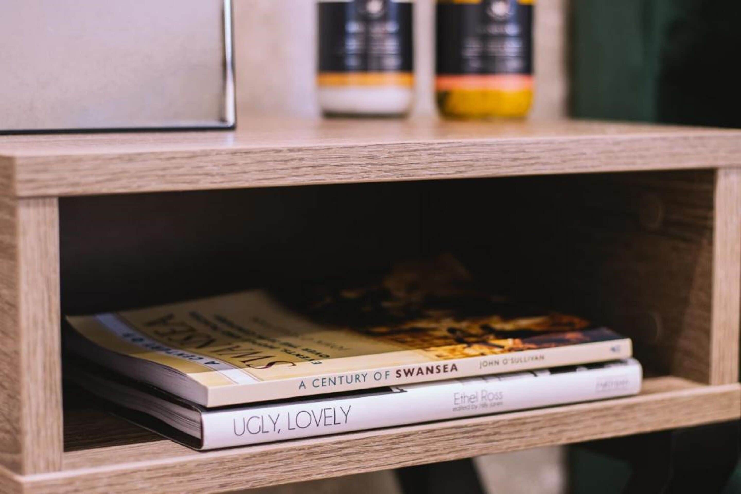 A wooden shelf with books and two bottles.