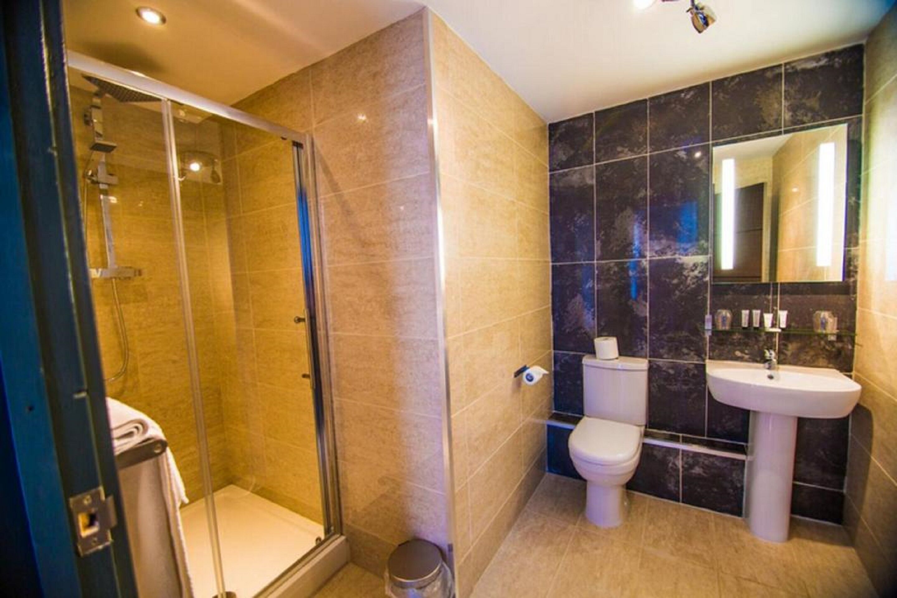 A modern bathroom with a glass-enclosed shower, a toilet, and a sink.