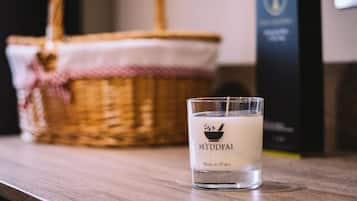 Una vela con la inscripción "MYDDFAI" y "Hecho en Gales" sobre una superficie de madera, con una cesta de mimbre al fondo.