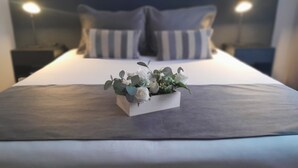 A neatly made bed with a floral arrangement in a white box, a dark headboard, and two bedside lamps. - Waldorf Hotel (Buenos Aires)