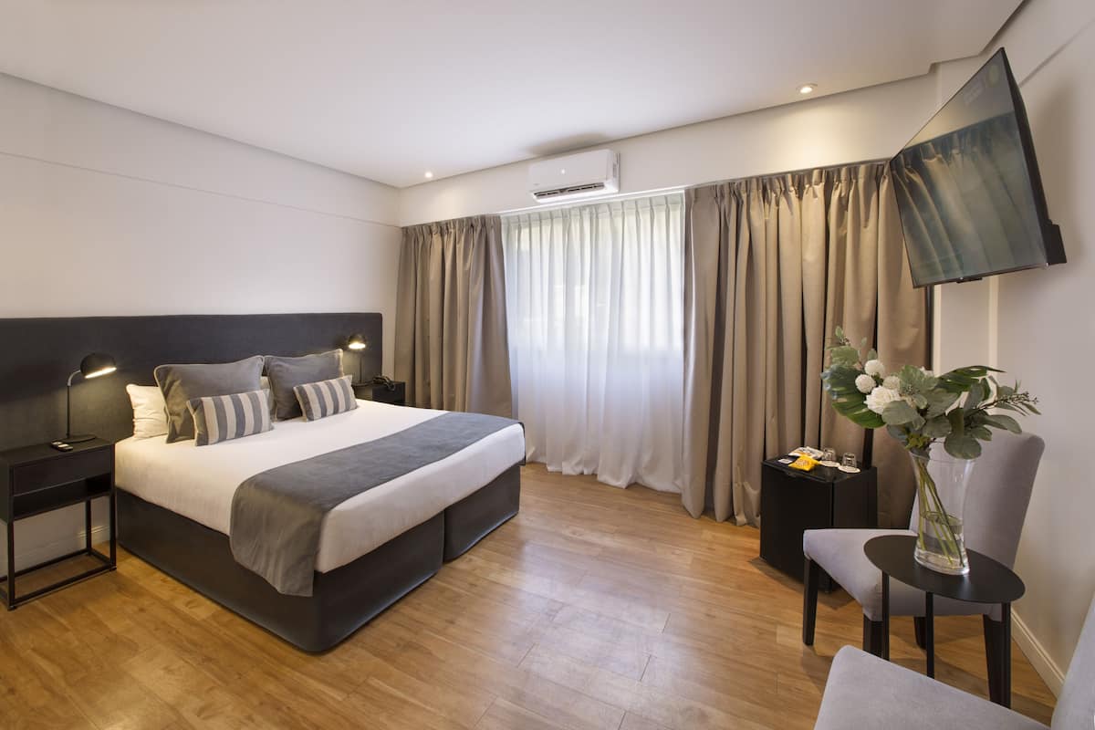 Un dormitorio moderno con una cama grande, mesitas de noche, un televisor de pantalla plana y un florero con flores.