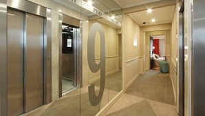 An interior corridor with a large '9' sign, elevators, and a glimpse of a room with a suitcase. - Waldorf Hotel (Buenos Aires)