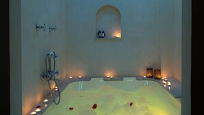 A spa room with a large bathtub, candles, and a clock. - Alcoba del Rey de Sevilla Boutique Hotel (Seville)