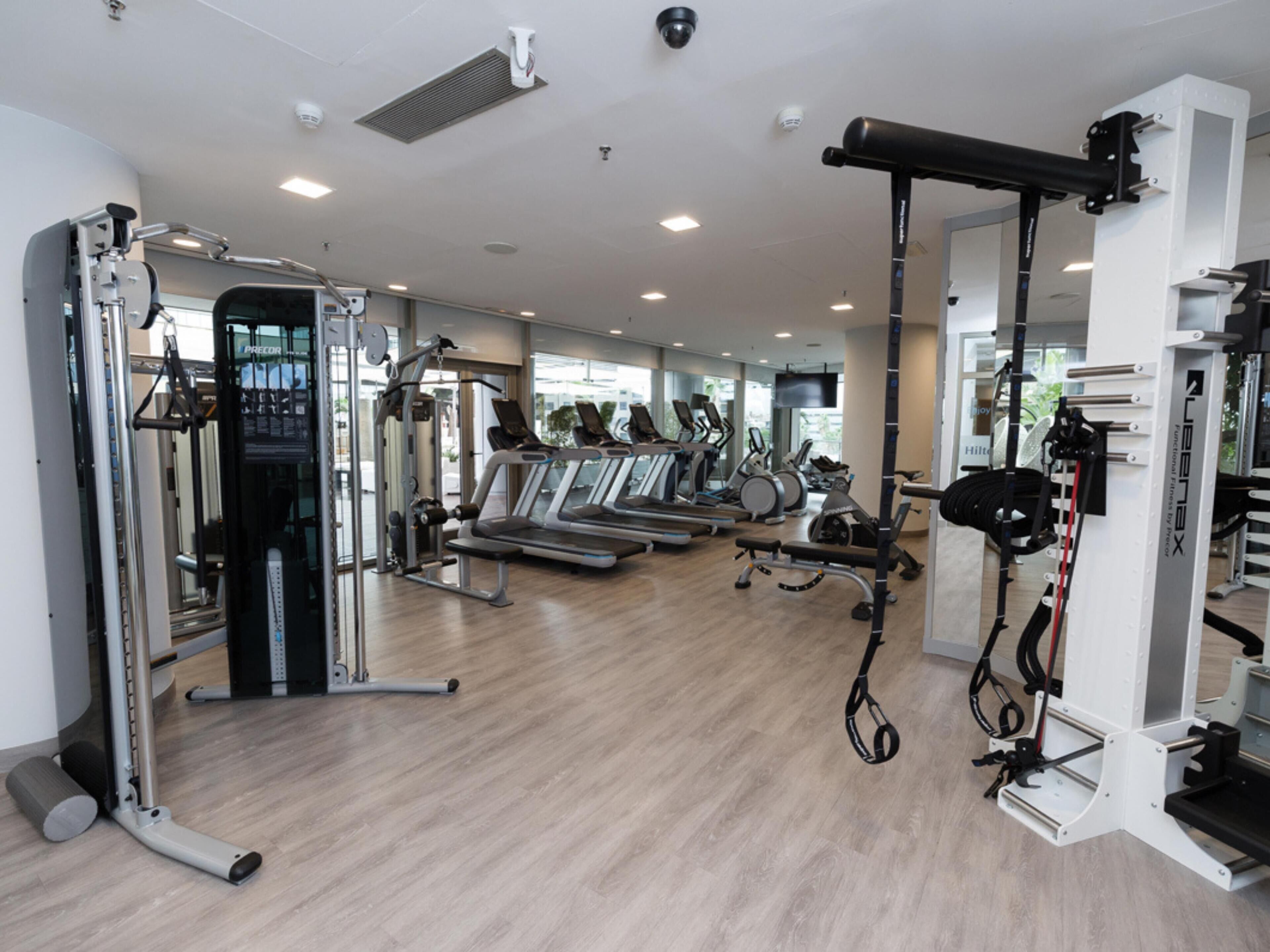 Uma academia moderna com máquinas de cardio, equipamentos de musculação e um interior limpo e bem iluminado.