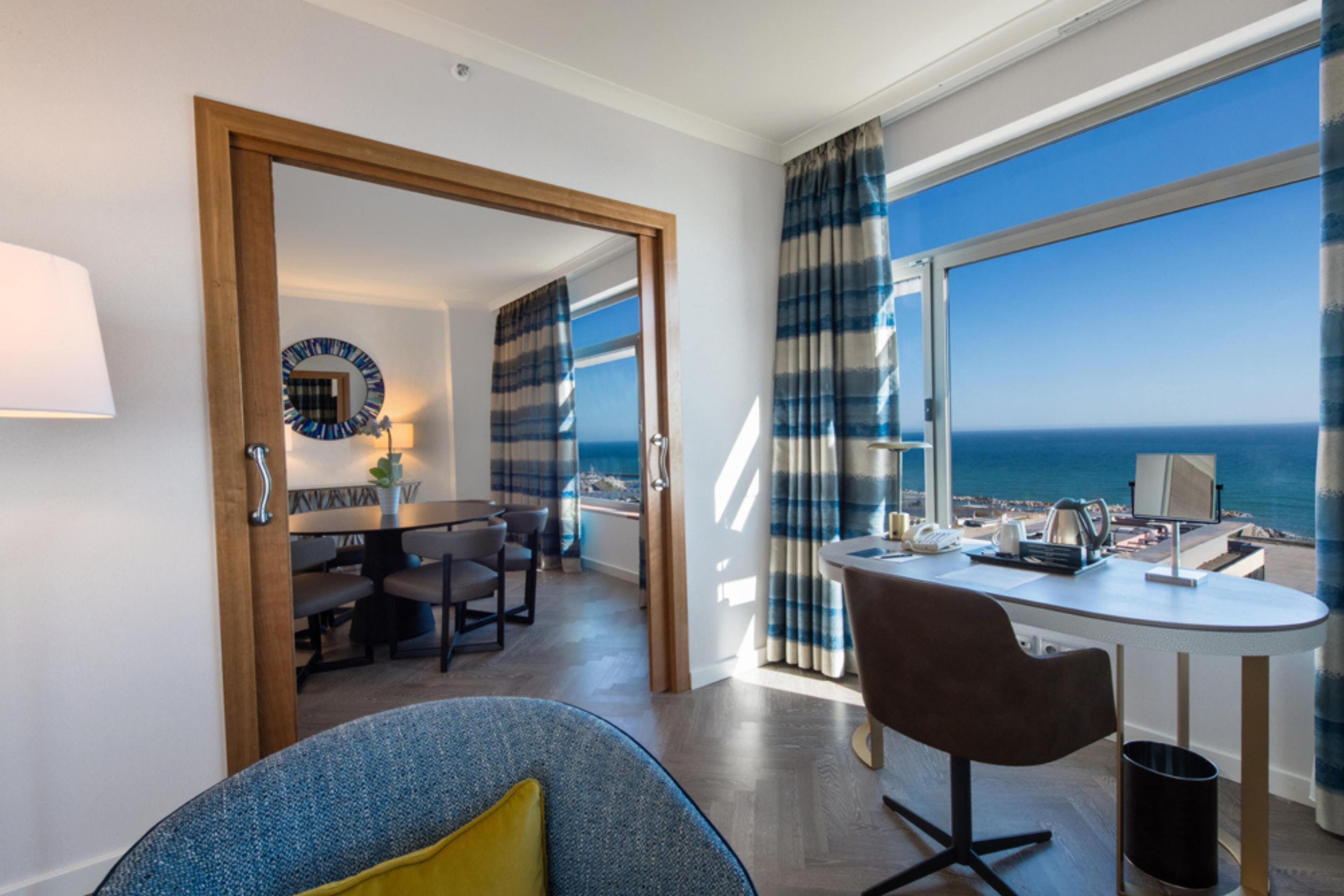 Een moderne kamer met een eethoek, een bureau en uitzicht op zee.