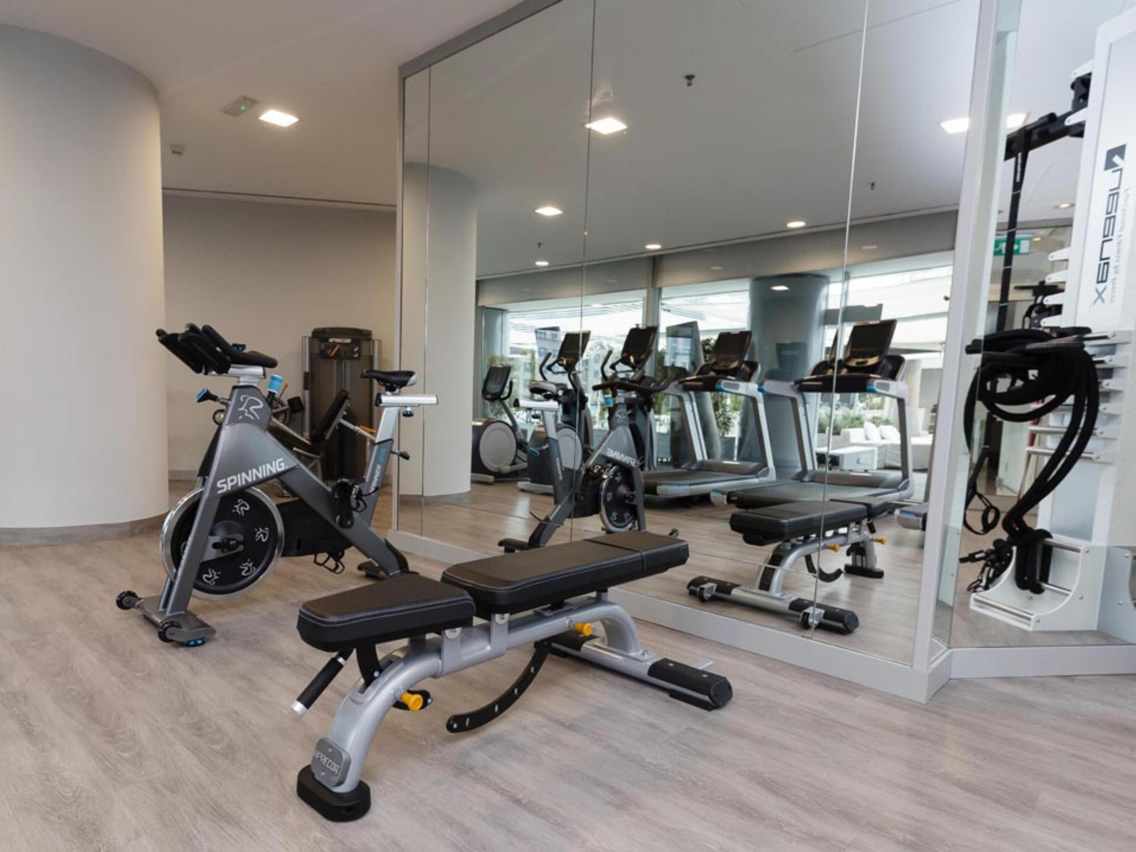 A gym with a spinning bike, treadmills, and a mirrored wall.