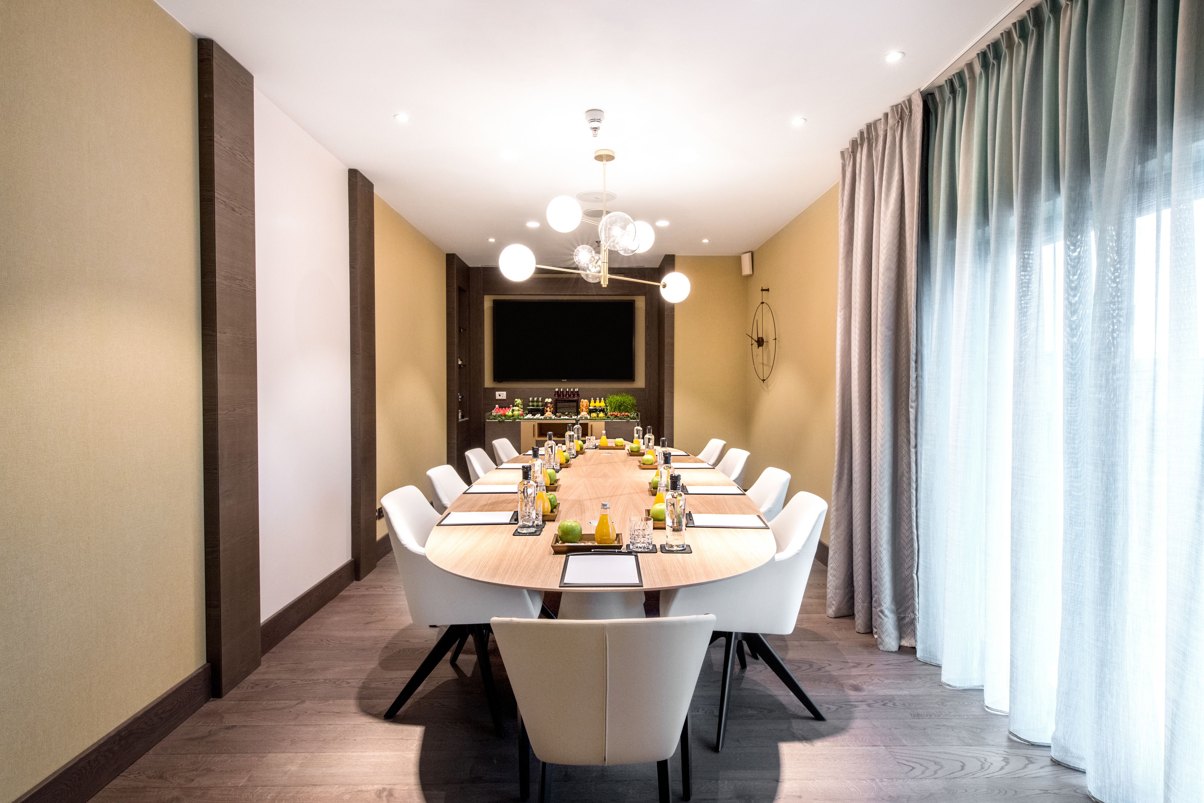 A modern dining room with a round table, white chairs, and a chandelier.