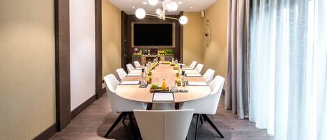 A modern dining room with a round table, white chairs, and a chandelier.