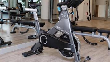 A stationary bike in a gym with a mirrored wall and exercise equipment in the background.
